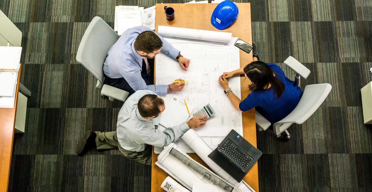 Un equipo de trabajo revisa planos y números en una mesa de reuniones