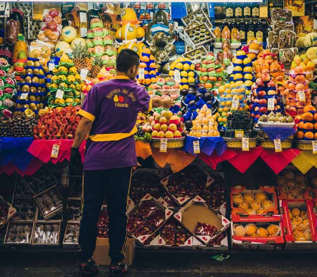 Puesto de mercado con su dueño acomodando la fruta